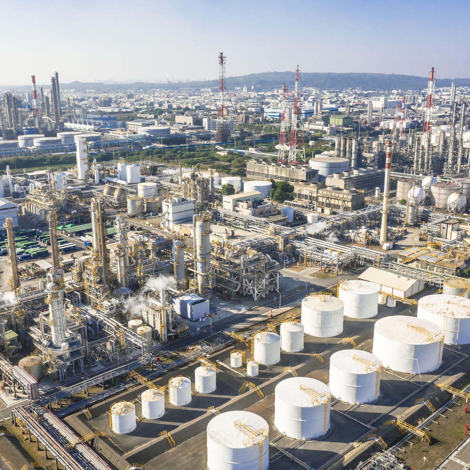 Aerial view of an industrial refinery complex with large storage tanks and pipelines. Aerial view of an industrial refinery complex with large storage tanks and pipelines.